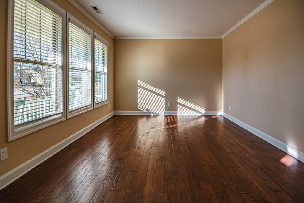 Sunlight falling through tall windows onto an empty wooden floor