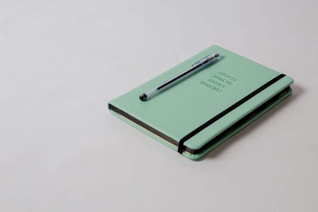 Pen lying across a closed mint-green notebook