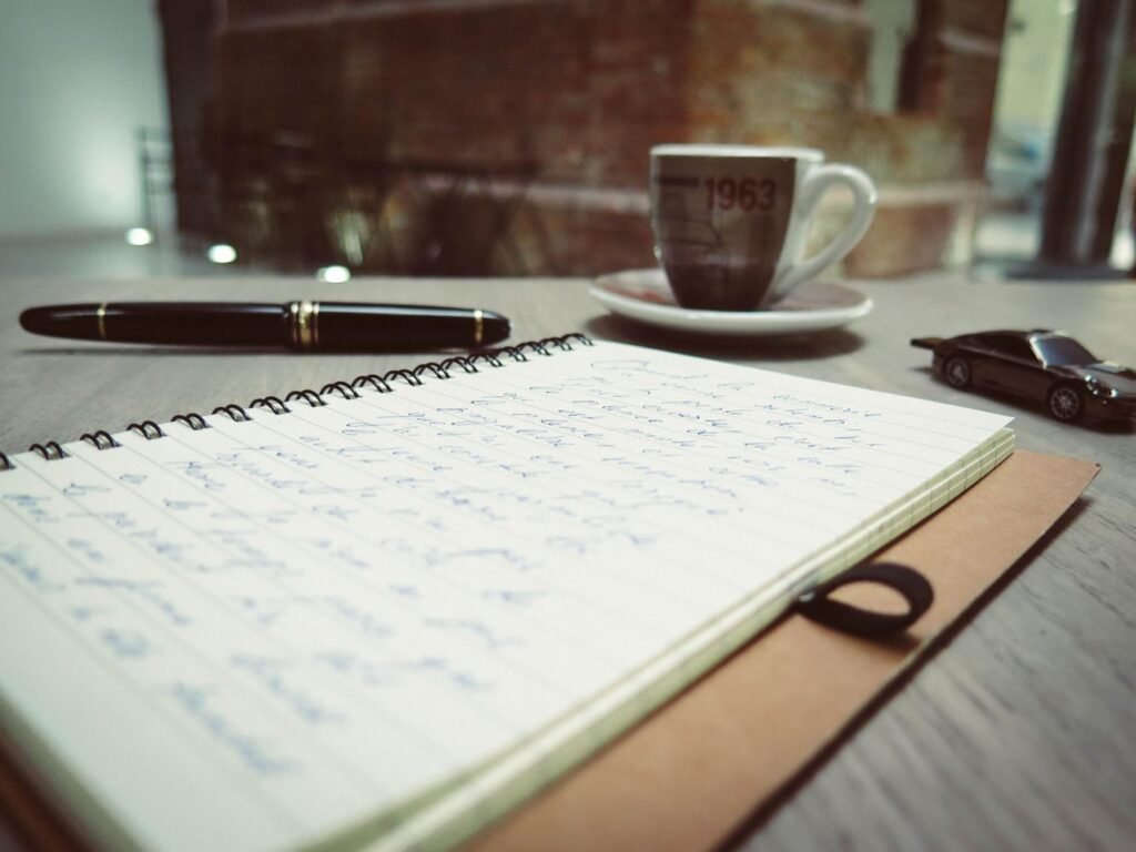 Handwritten notes in an open notebook beside a coffee cup