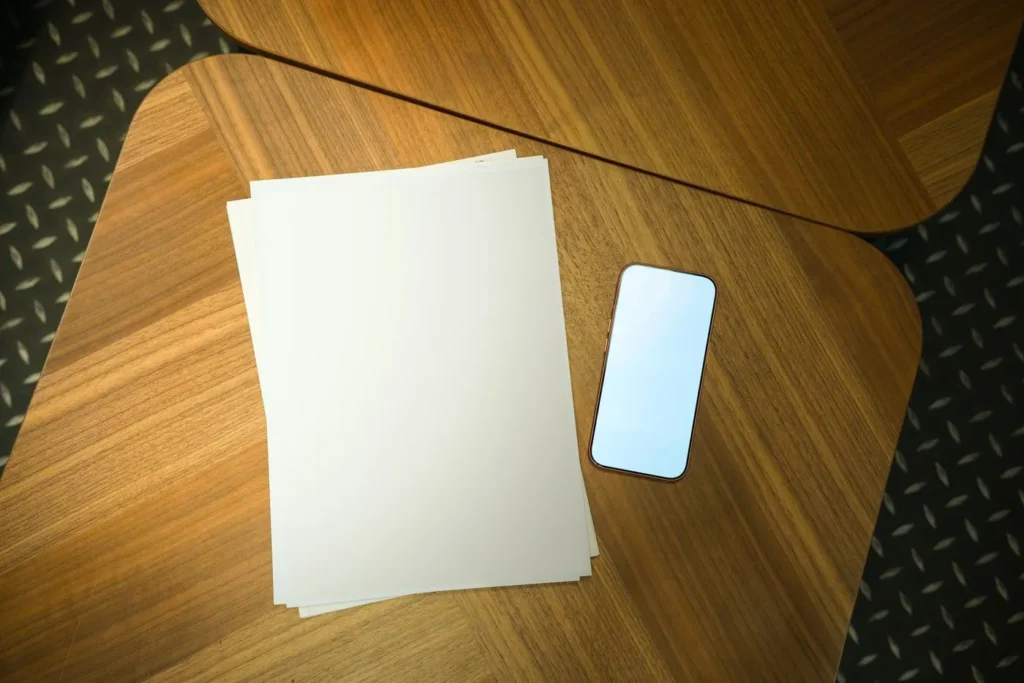 Blank paper and a smartphone resting on a round wooden table