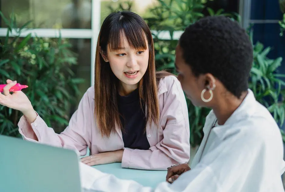 Two women discussing a task beside a laptop