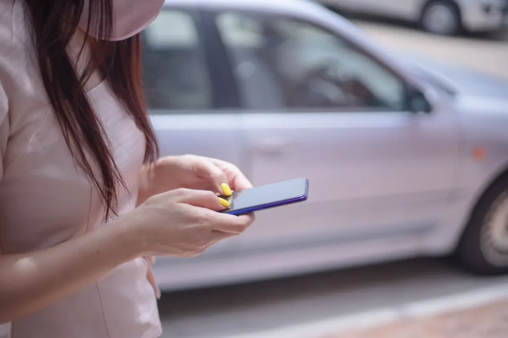 Woman using a smartphone beside a parked car