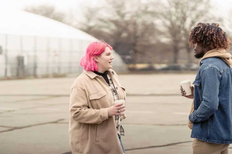 Two people talking outdoors while holding takeaway coffee cups