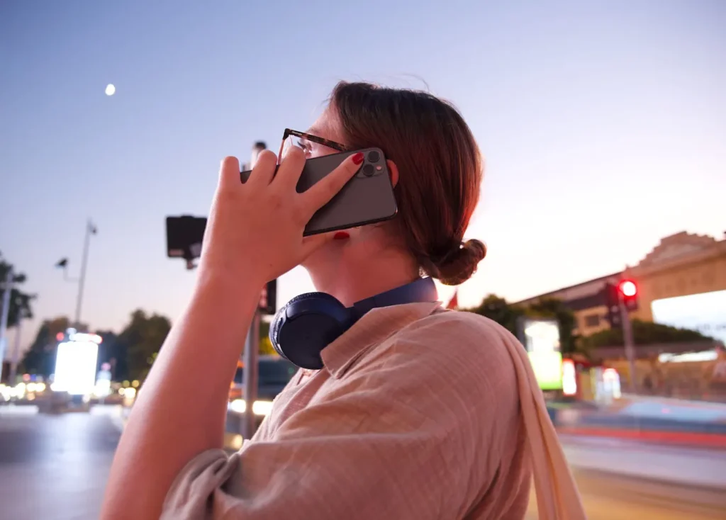 Woman holding a phone to her ear with headphones around her neck