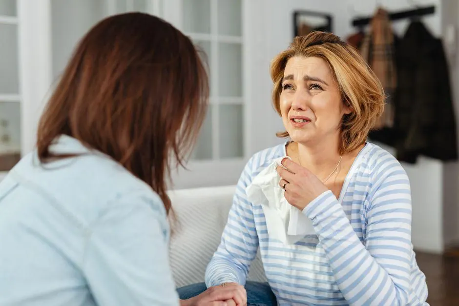 Woman holding a tissue while a friend comforts her