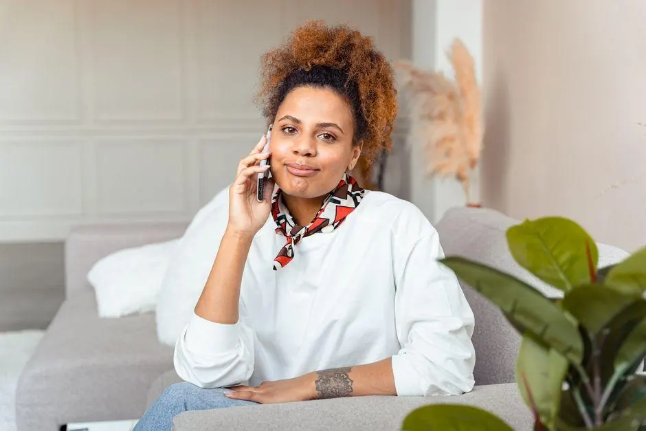 Woman speaking on a phone while seated on a sofa