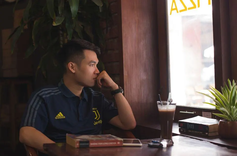 Man sitting alone at a cafe table beside a window