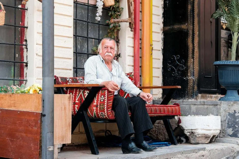 Man sitting on an outdoor bench beside a cafe