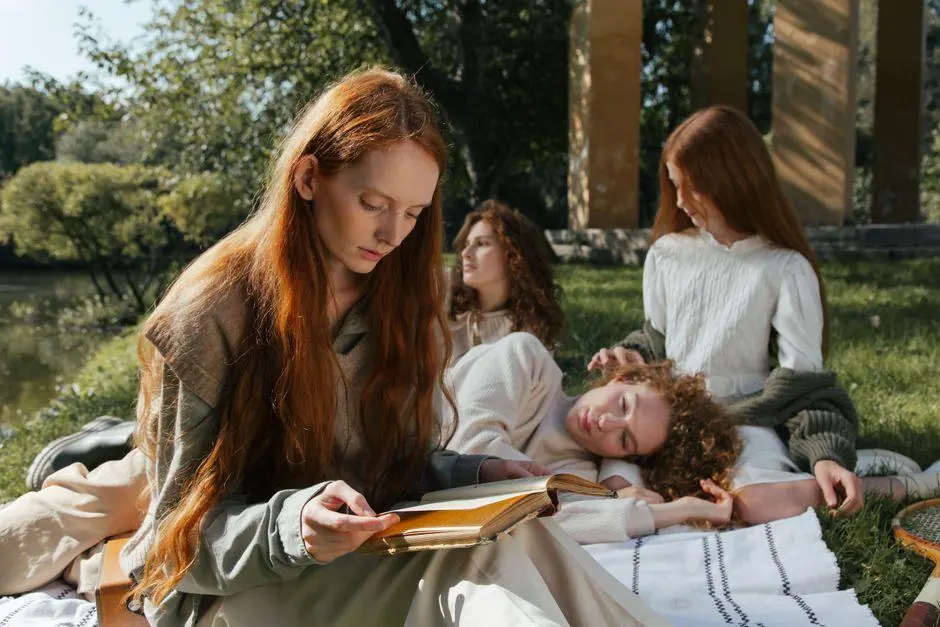 Four women reading and relaxing together outdoors beside a lake