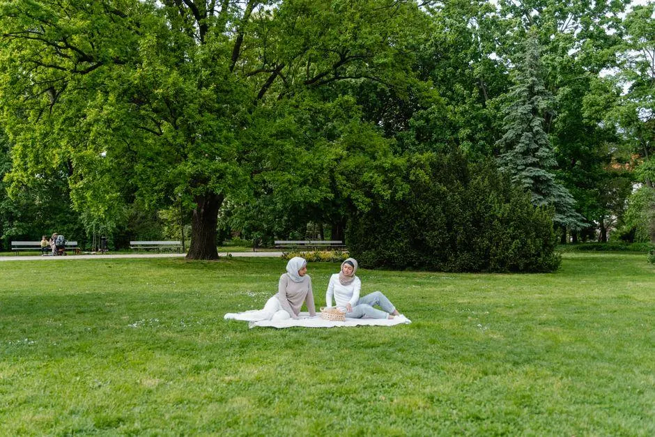 Two women sharing a picnic beneath trees in a park