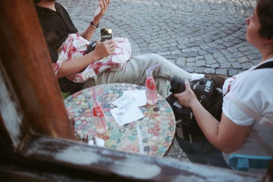 Two people seated at an outdoor cafe table with cameras