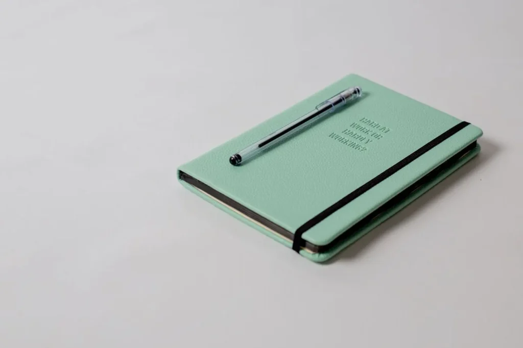 Pen lying across a closed mint-green notebook