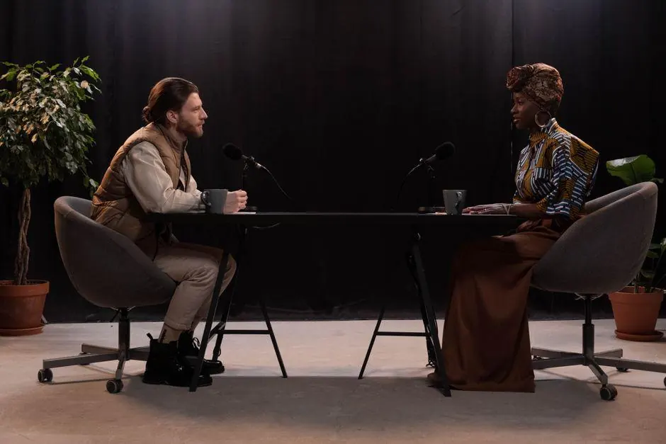 Two adults seated across a table with microphones