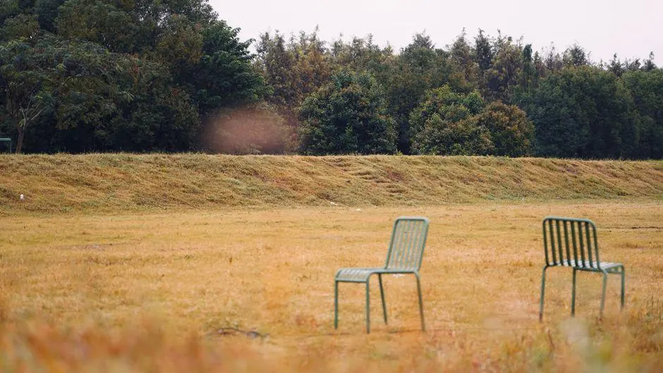Two empty metal chairs standing in a grassy field