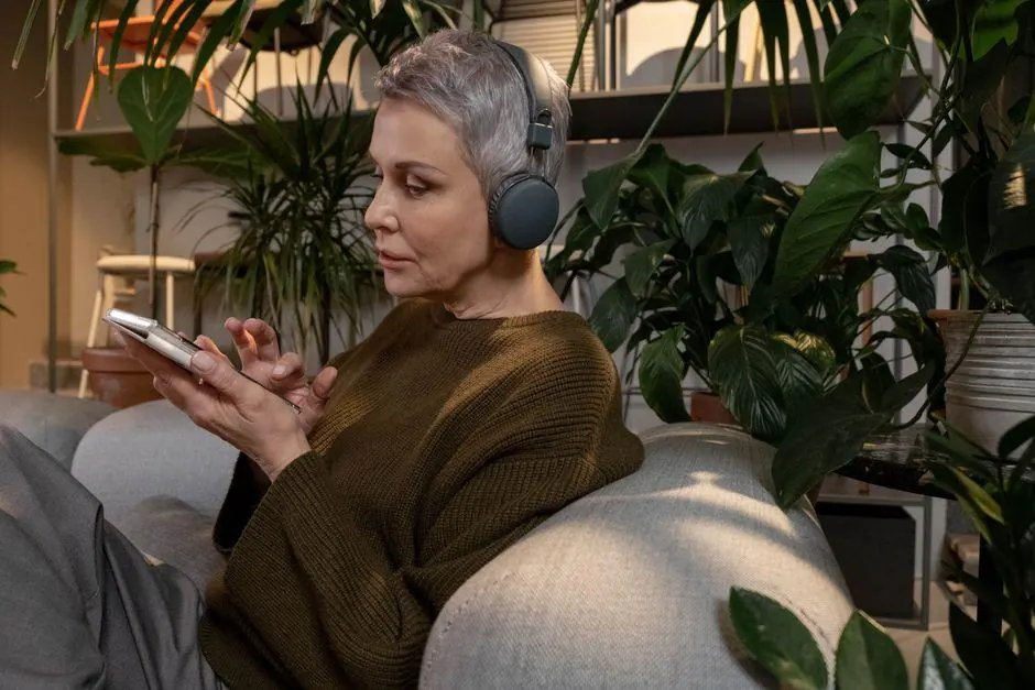 Woman wearing headphones and using a phone on a sofa