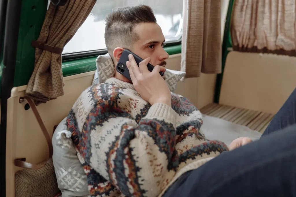 Man holding a phone to his ear beside a curtained window