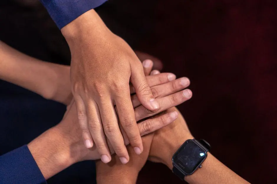 Several hands stacked together above a table