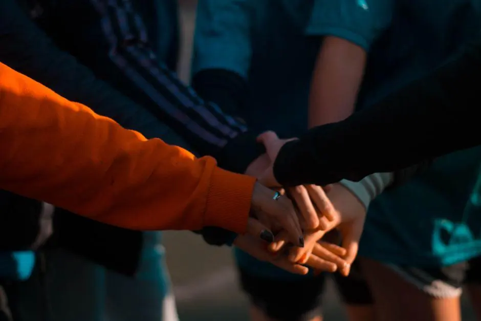 Several people stacking their hands together outdoors