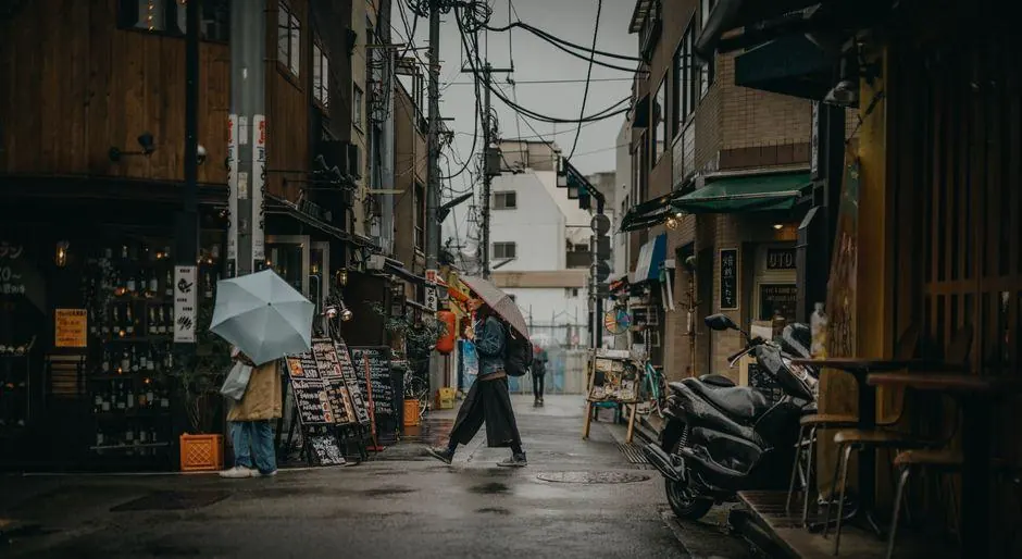 People carrying umbrellas along a narrow rainy street